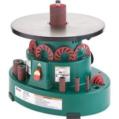 a machine that is sitting on top of a green stand with red and black wheels