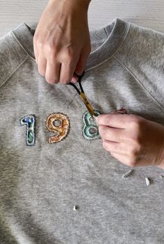 someone is cutting out the numbers on a sweatshirt with scissors and thread to make it look like they have been embroidered onto