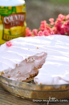 a cake with white frosting and pink flowers in the background