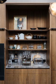 a kitchen with wooden shelves filled with dishes and coffee maker on top of the counter