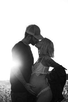 a man and woman kissing while standing next to each other in front of the sun