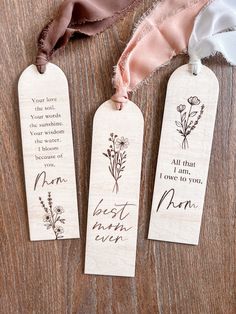 three wooden bookmarks with handwritten words and flowers on them sitting on a table