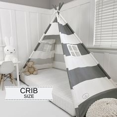 a child's teepee tent bed with grey and white stripes on it, next to a small table