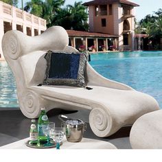 a white bench sitting next to a pool with bottles and glasses on top of it