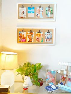 two pictures hanging on the wall above a desk with a lamp and other items in front of it