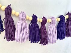 several tasselled beads hanging from a string on a white wall with purple and lavender colors