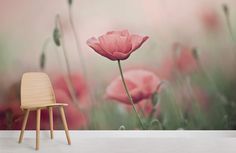 a chair sitting in front of a wall mural with pink flowers on it and green grass