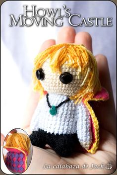 a crocheted doll with blonde hair wearing a white shirt and black pants, holding it in her hand