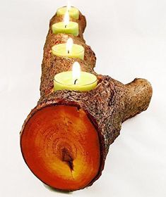 three lit candles are placed on a piece of wood that has been cut in half