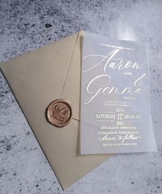 a wedding card with a wax stamp on it sitting next to an envelope and seal