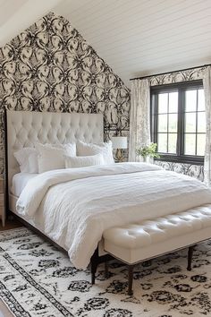 a large white bed sitting in a bedroom next to a black and white wallpaper