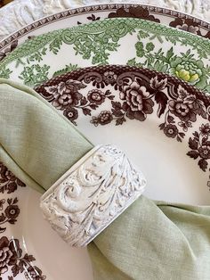 the napkins are folded on top of the plate with green and brown floral designs