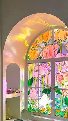 an arched glass window with flowers painted on it's side and the light coming through