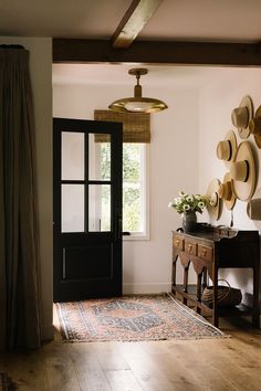 a room with a table, chair and hat rack on the wall next to a door