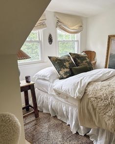 a bed with white sheets and pillows in a bedroom