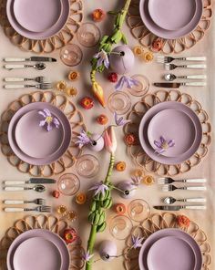 the table is set with purple plates and silverware