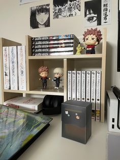 a desk with some anime figurines and books on the shelves next to it