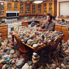 a man sitting at a table surrounded by rocks in the middle of a kitchen area