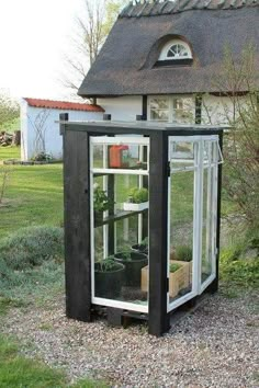 a small black and white building with plants inside