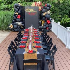 a long table is set up with black and red plates, napkins and candles