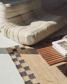 a white couch sitting on top of a rug next to a wooden table and chair