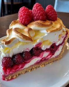 a piece of pie with raspberries and meringue on top sits on a white plate