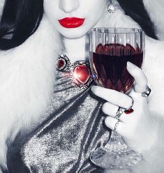 a woman holding a glass of wine in her right hand and red lipstick on her left