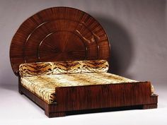 a bed with an intricate headboard and foot board made out of wood, sitting in front of a gray wall