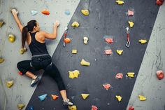 a woman climbing up the side of a rock wall with her hands in the air