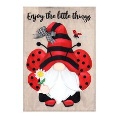 a red and black ladybug gnome with flowers on it's head, says enjoy the little things