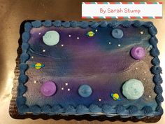 a cake that is decorated with planets and stars on top of the icing sheet