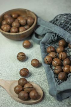 some nuts are sitting on the ground next to a wooden spoon and bag with one nut in it