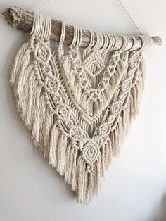 a white wall hanging with some tassels on it's sides and a piece of wood sticking out of the side