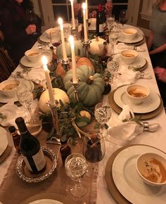 a table set for thanksgiving dinner with pumpkins and gourds on the centerpiece