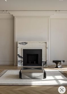 a living room with white walls and a fireplace in the center, surrounded by wood flooring