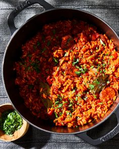 a large pot filled with lots of food next to a wooden spoon on top of a table