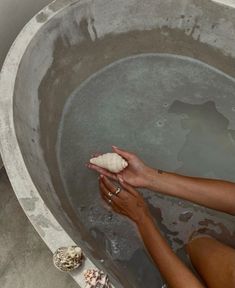 a woman is cleaning her hands in a bathtub with soap and seashells