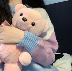 a woman holding a pink teddy bear in her arms