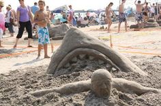 a sand sculpture on the beach with people in the background