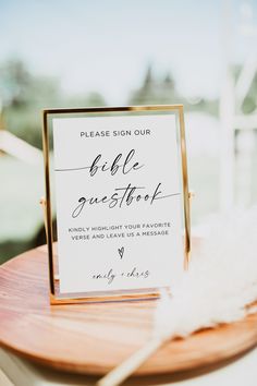 a sign that is on top of a wooden table next to a white and black feather