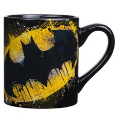 a black and yellow batman coffee mug with paint splattered on it's side