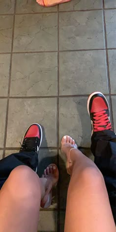 two people standing next to each other on a tile floor with their feet up in the air