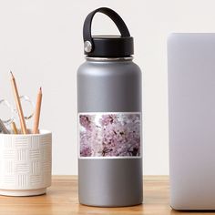 a close up of a water bottle on a table next to a cup with pencils