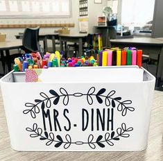 a white box with the word mrs dinh on it and lots of markers in it