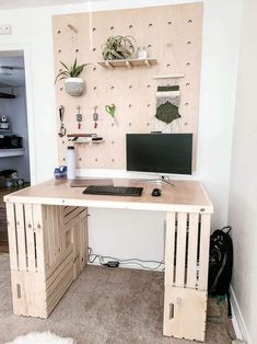 a computer desk made out of pallets and wooden crates with plants on the wall