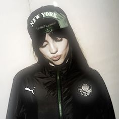 a woman wearing a black jacket and green hat