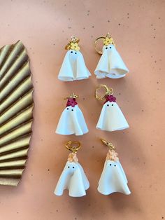 six ghost keychains sitting on top of a table next to a seashell