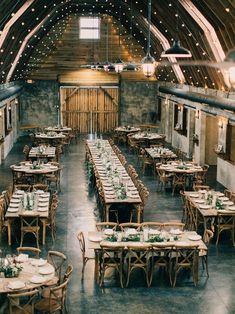 the inside of a barn with tables and chairs set up for an elegant wedding reception