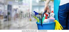 a person holding a blue bucket filled with cleaning supplies