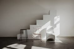 a chair sitting on top of a white floor next to a set of stairs in a room